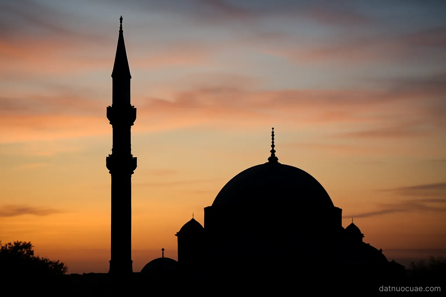 A minaret and dome silhouetted against an evening sky, wide view, no readable text